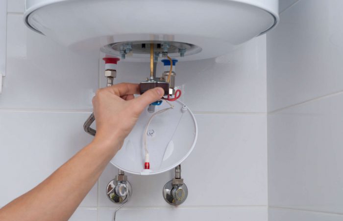 master holds a thermostat from an electric boiler in his hand